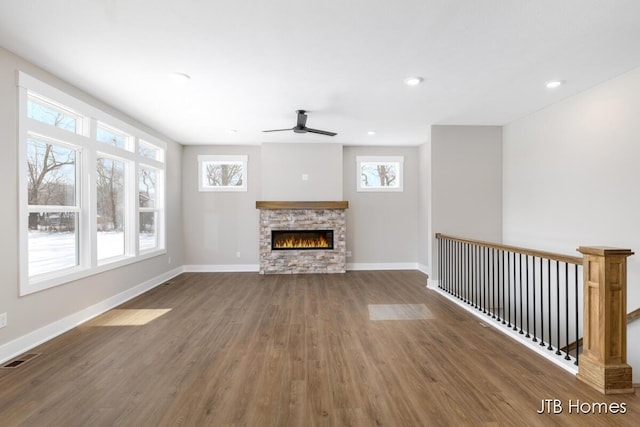 unfurnished living room with a fireplace, visible vents, a ceiling fan, wood finished floors, and baseboards