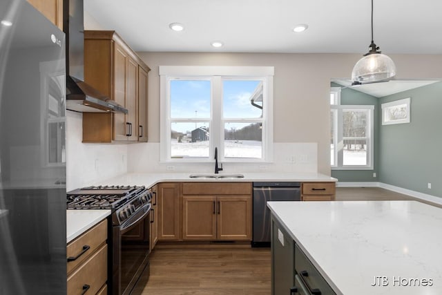 kitchen featuring a sink, wall chimney range hood, stainless steel dishwasher, black range with gas stovetop, and decorative backsplash