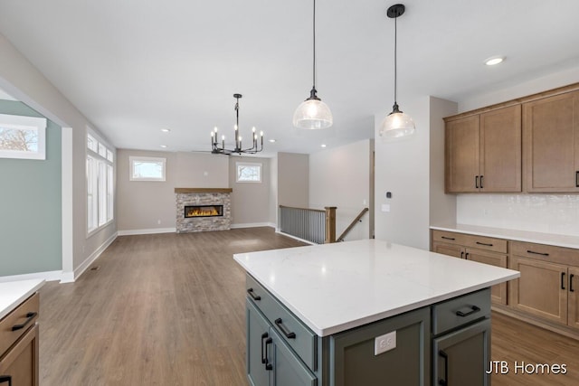 kitchen with light wood-type flooring, light countertops, hanging light fixtures, and decorative backsplash