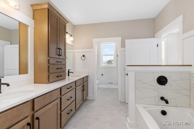 bathroom featuring a bathtub, visible vents, a sink, and toilet