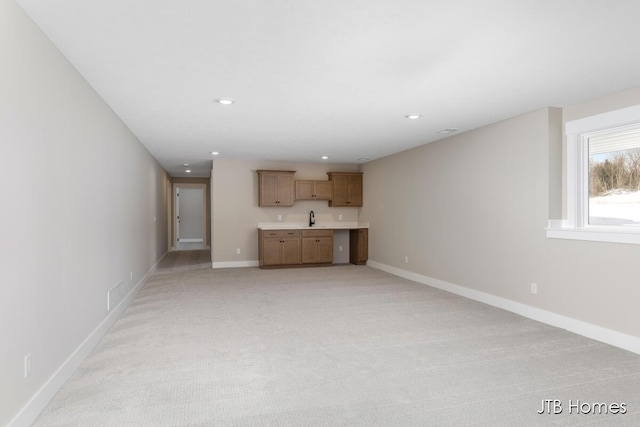 unfurnished living room featuring recessed lighting, light colored carpet, a sink, and baseboards