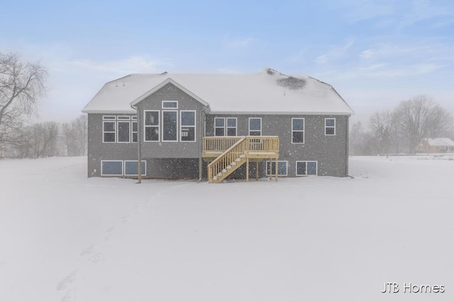 snow covered property with brick siding and stairs