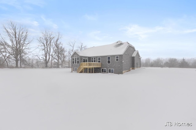 snow covered rear of property featuring stairs and a wooden deck