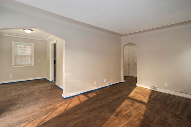 empty room with ornamental molding and dark wood-type flooring