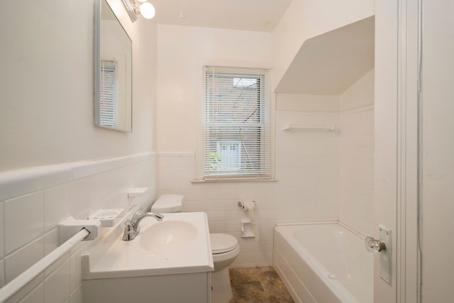 bathroom featuring a bath, vanity, toilet, and tile walls