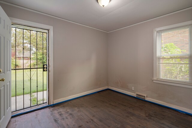 empty room featuring a healthy amount of sunlight, dark hardwood / wood-style flooring, and ornamental molding