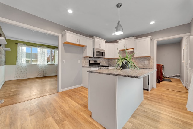 kitchen with white cabinets, decorative light fixtures, light wood-type flooring, and appliances with stainless steel finishes