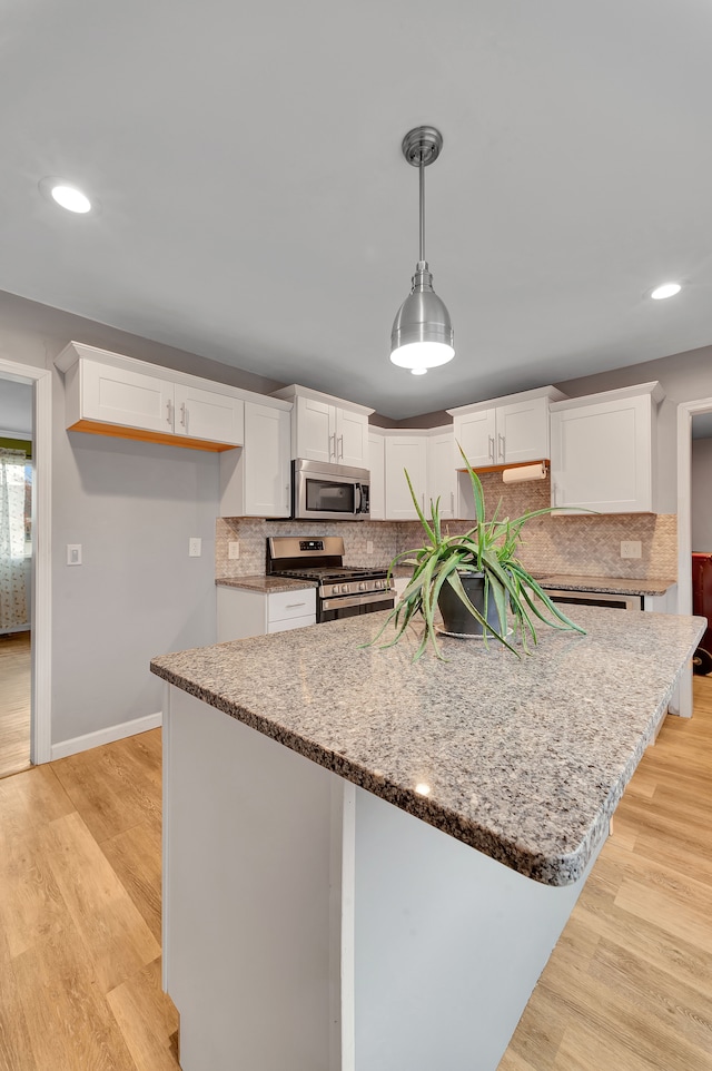 kitchen with white cabinets, appliances with stainless steel finishes, light hardwood / wood-style floors, and tasteful backsplash