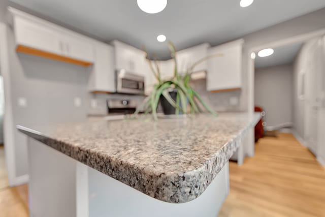 kitchen with white cabinets, light wood-type flooring, and kitchen peninsula