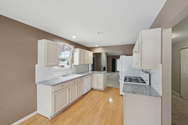 kitchen with light stone counters, white dishwasher, sink, and white cabinets