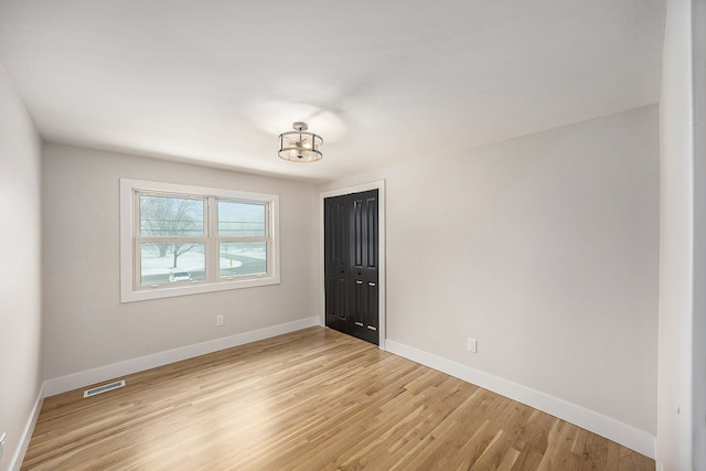 unfurnished room featuring light wood finished floors, visible vents, and baseboards