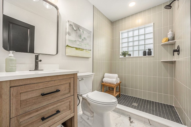 bathroom with marble finish floor, tiled shower, vanity, and toilet