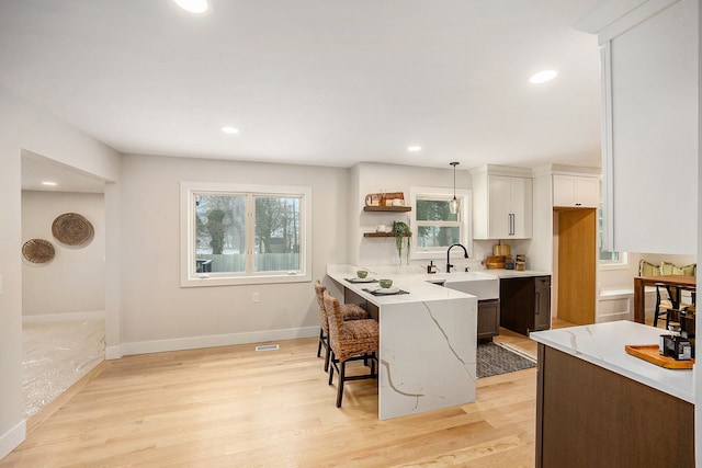 kitchen with a breakfast bar, plenty of natural light, light wood-style floors, and a sink