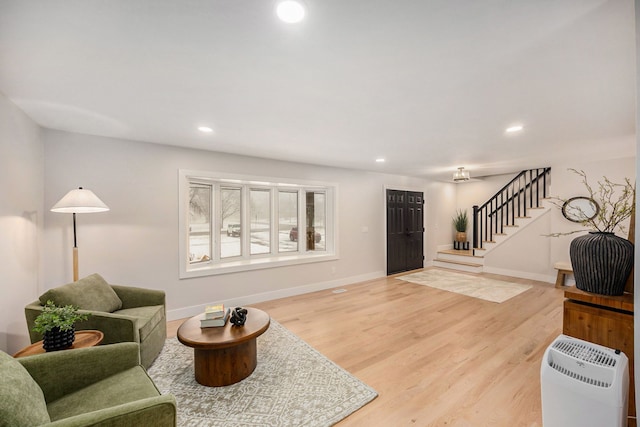 living room with stairs, light wood-style flooring, recessed lighting, and baseboards