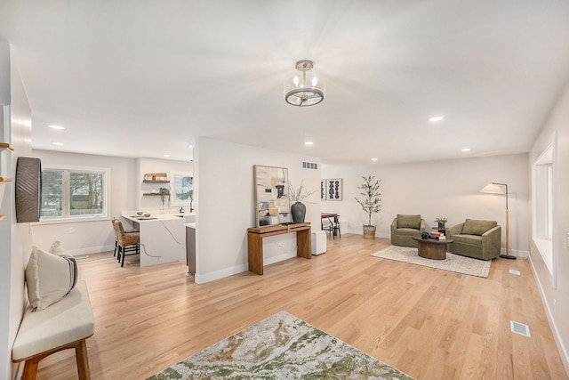 living room featuring recessed lighting, light wood-style flooring, and visible vents