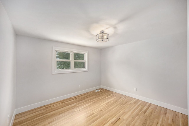 empty room with visible vents, light wood-style floors, and baseboards