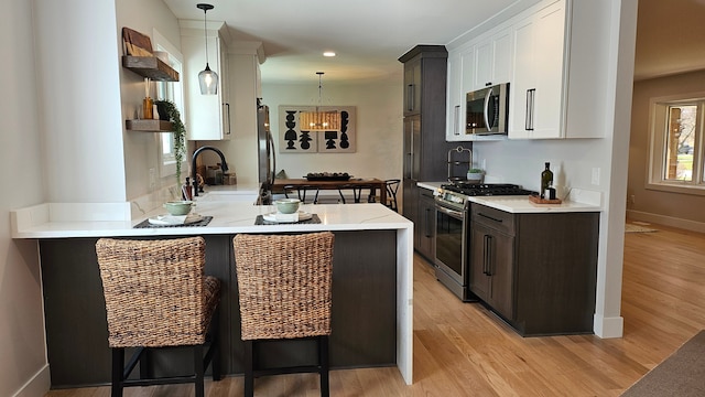 kitchen featuring a breakfast bar area, white cabinetry, appliances with stainless steel finishes, and light wood-style flooring