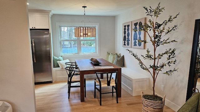 dining area with baseboards, light wood-type flooring, and a chandelier