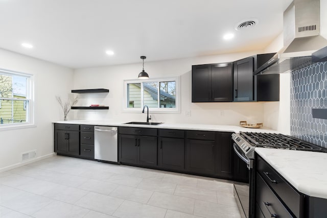 kitchen featuring stainless steel appliances, sink, wall chimney range hood, hanging light fixtures, and light tile patterned flooring