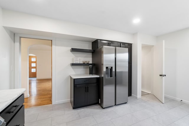 kitchen with light stone countertops, stainless steel fridge with ice dispenser, and light hardwood / wood-style flooring