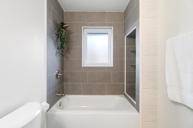 bathroom with toilet and tiled shower / bath