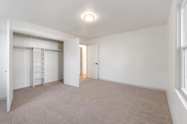 unfurnished bedroom with multiple windows, light carpet, and a closet