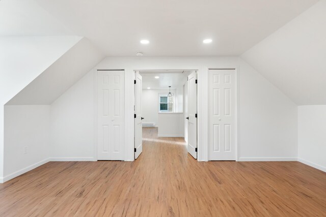 bonus room featuring light wood-type flooring, a baseboard radiator, and vaulted ceiling