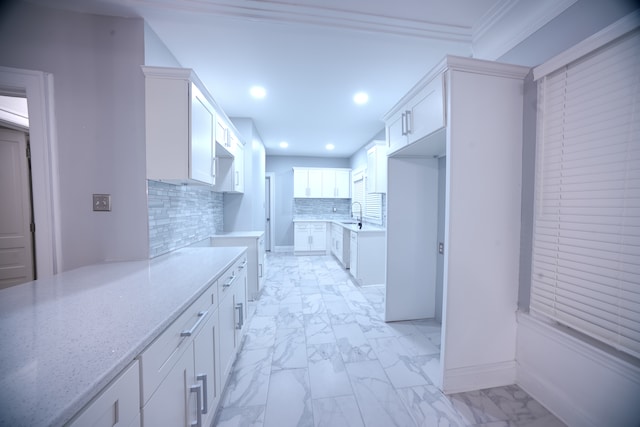 kitchen with light stone countertops, white cabinets, and ornamental molding