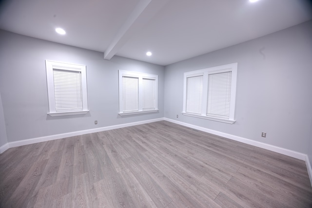 empty room featuring beam ceiling and light wood-type flooring