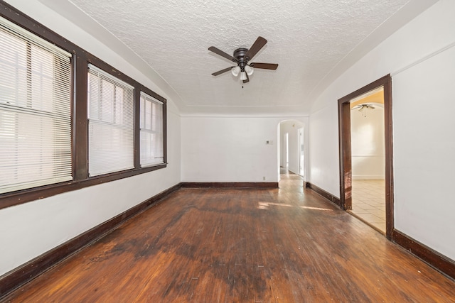 empty room with ceiling fan, dark hardwood / wood-style flooring, and a textured ceiling