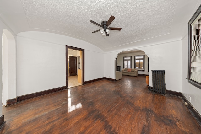 unfurnished living room with dark hardwood / wood-style floors, ceiling fan, a textured ceiling, and vaulted ceiling