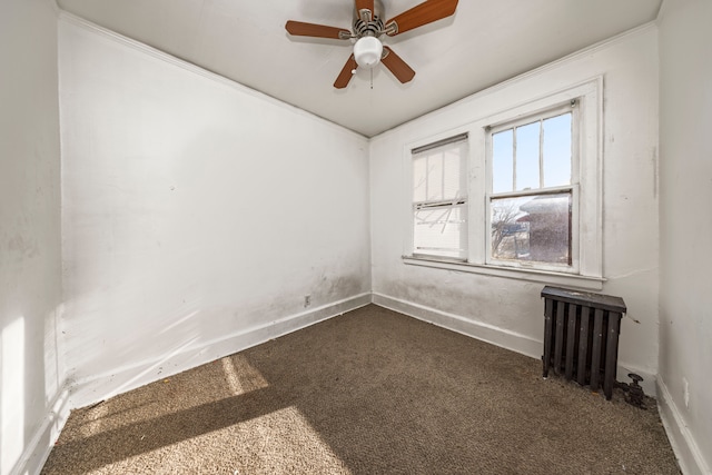 spare room featuring radiator heating unit, dark carpet, and ceiling fan