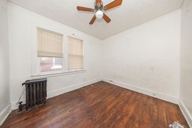 unfurnished room with ceiling fan, radiator heating unit, dark hardwood / wood-style floors, and ornamental molding