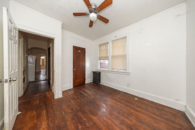 unfurnished bedroom with a textured ceiling, white refrigerator, ceiling fan, and dark wood-type flooring