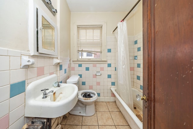 full bathroom featuring tile patterned flooring, shower / bath combination with curtain, tile walls, and sink