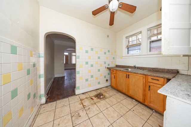 kitchen with light tile patterned flooring, ceiling fan, tile walls, and sink