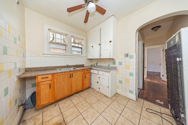 kitchen featuring white cabinetry, sink, ceiling fan, and tile walls