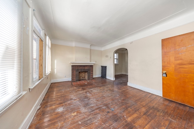 unfurnished living room featuring a fireplace, plenty of natural light, and dark wood-type flooring