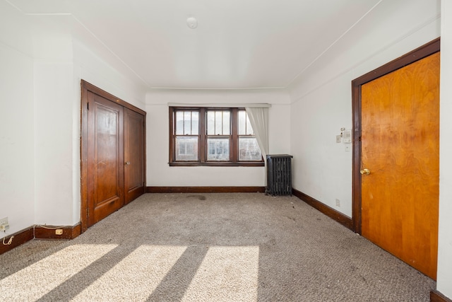 unfurnished bedroom featuring light carpet, a closet, and radiator heating unit