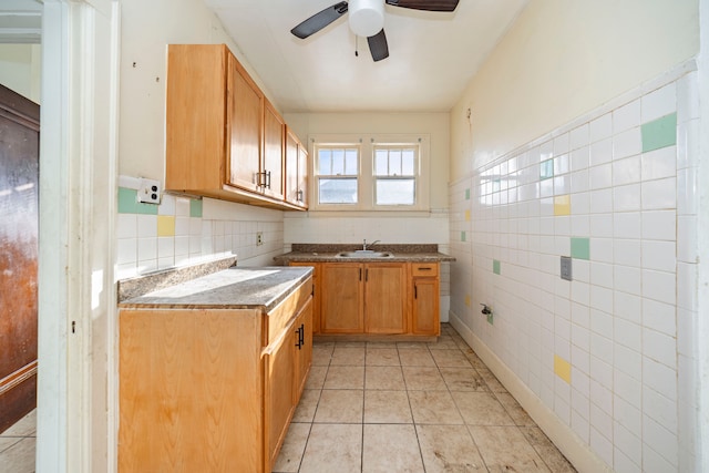 kitchen with light tile patterned floors, tile walls, ceiling fan, and sink