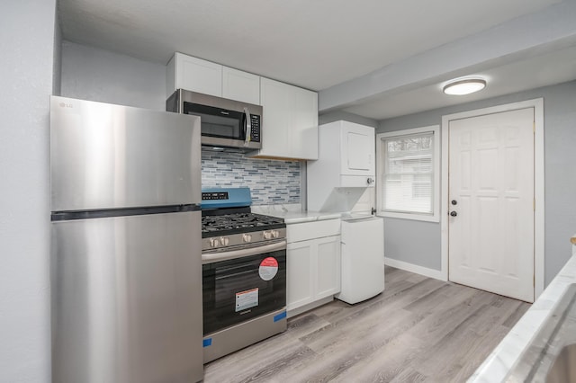 kitchen with decorative backsplash, appliances with stainless steel finishes, stacked washer and clothes dryer, white cabinets, and light hardwood / wood-style floors