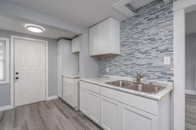 kitchen with white cabinets, light hardwood / wood-style floors, tasteful backsplash, and sink