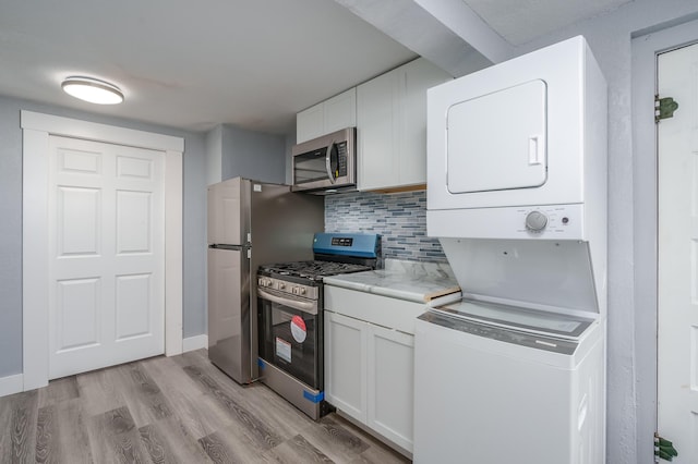 kitchen featuring stacked washer / dryer, white cabinets, stainless steel appliances, and light hardwood / wood-style floors