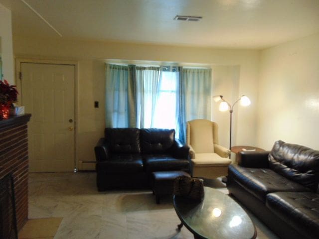 living room with a fireplace, light carpet, and baseboard heating