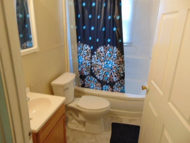 full bathroom with shower / bath combo with shower curtain, vanity, and toilet