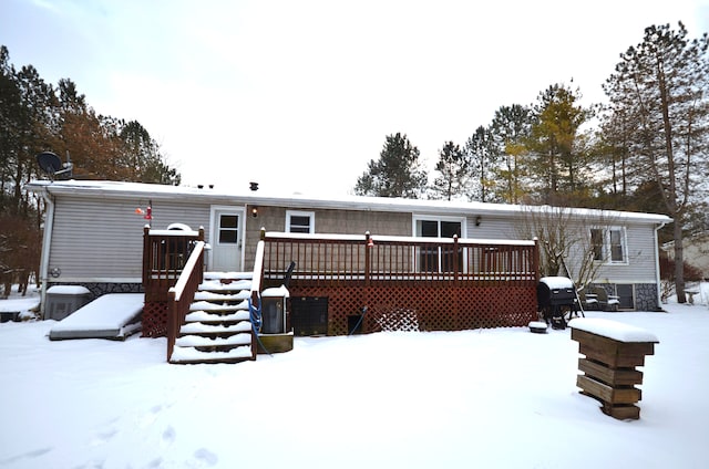 snow covered property with cooling unit and a wooden deck