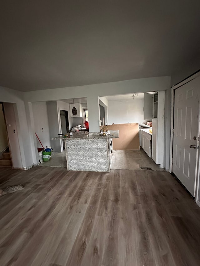 kitchen with kitchen peninsula, white cabinets, and hardwood / wood-style flooring