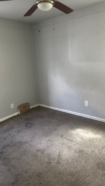 spare room featuring ceiling fan and dark colored carpet