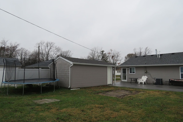 rear view of property with a patio area, a trampoline, a yard, and central air condition unit