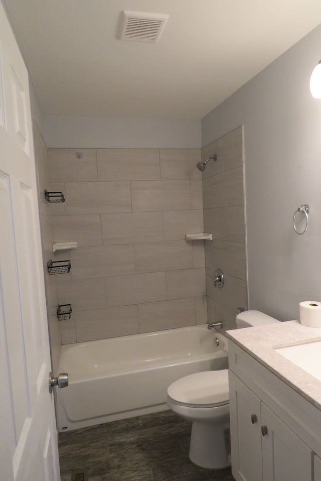 full bathroom featuring vanity, hardwood / wood-style flooring, toilet, and tiled shower / bath combo